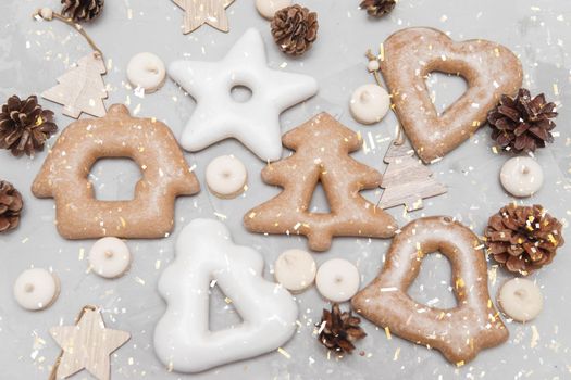 Banner for Christmas and New Year gingerbread stars, houses, Christmas trees, toys on a gray concrete background, Christmas lights bokeh in the foreground.