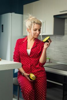 the blonde vegan woman cuts avocado in kitchen