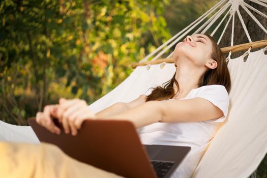 woman with laptop lies in hammock freelance travel. High quality photo