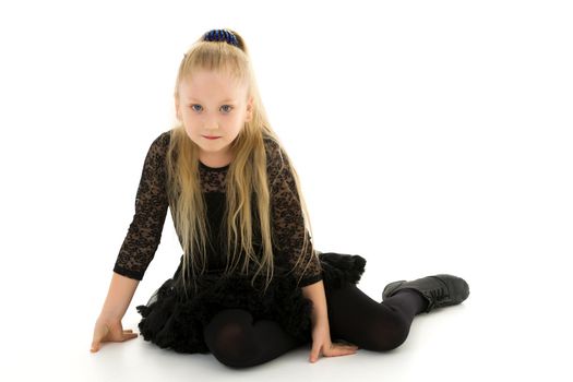 Beautiful little girl is sitting on the floor in the studio. The concept of a happy childhood, beauty and fashion. Isolated on white background.