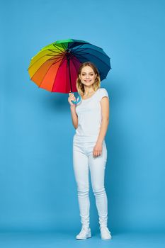fashionable woman with umbrella rainbow colors posing blue background. High quality photo