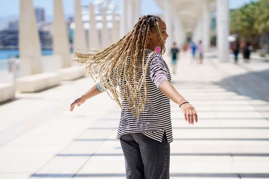 Black female moving her coloured braids in the wind. Typical African hairstyle.