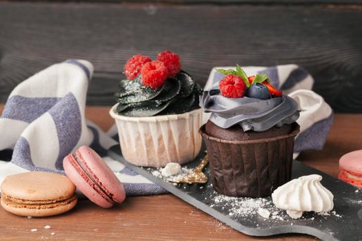 Delicious raspberry and caramel cupcakes on dark background