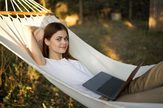 woman lies in a hammock with laptop on nature vacation travel. High quality photo
