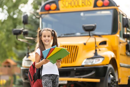 Girl with backpack near yellow school bus. Transport for students