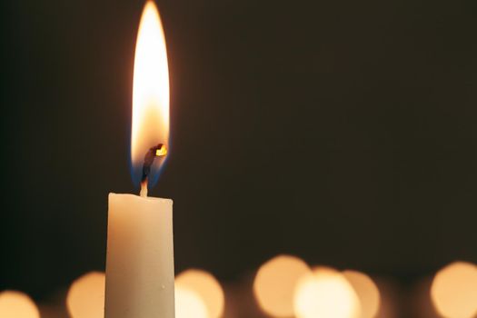 A single burning candle isolated with black background