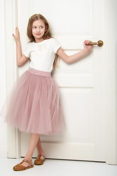 A nice little girl is standing by the door. The concept of family happiness and a home.