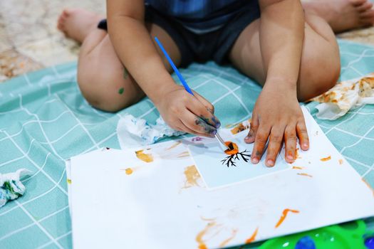 Focus on hands on paper. Children use paintbrushes to paint watercolors on paper to create their imagination and enhance their learning skills