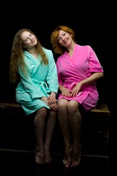 Daughter and mother in bath robes in a photo studio. The concept of relaxation, cosmetics. Isolated