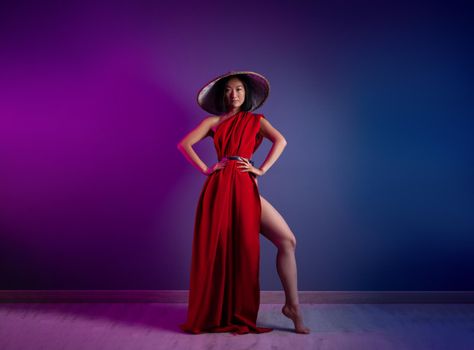 the asian woman in red cape and asian hat posing on bright neon background