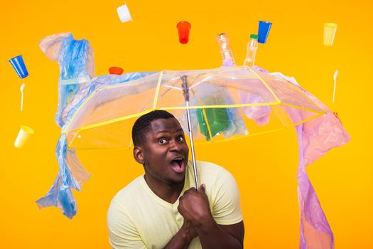 Plastic recycling problem, ecology and environmental disaster concept - Scared man screaming on yellow background with trash. He is worried about ecology disaster.