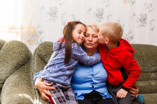 Grandmother and grandchildren sitting together on sofa in living room