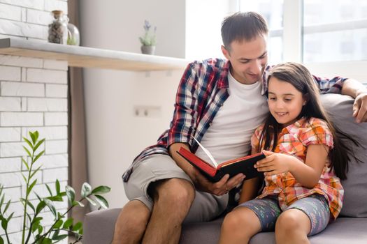 a young father with his little daughter reads the Bible