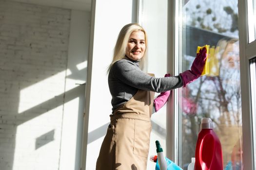 Cleaning service concept. Young woman with bottle of detergent in office