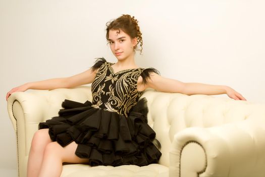 Beautiful teen girl very beautiful, smart dress sitting on the couch. The concept of style and fashion.