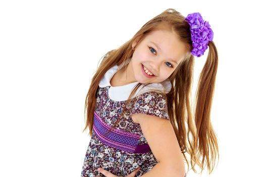 Happy little girl with a big purple bow on her head , and fancy dress. The girl bent her head to see her long beautiful hair.Isolated on white background.