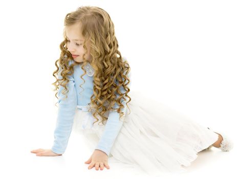 Beautiful little girl is sitting on the floor in the studio. The concept of a happy childhood, beauty and fashion. Isolated on white background.