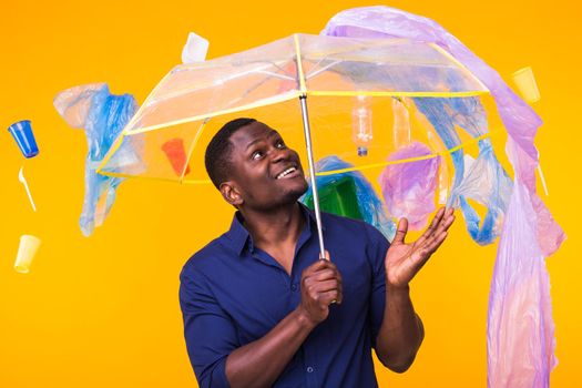 World Environment Day, plastic recycling problem and environmental disaster concept - Surprised african american man looking on trash on yellow.