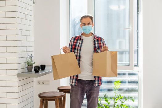 Delivery man holding paper bag with food, food delivery man in protective mask
