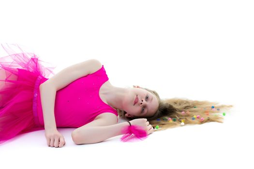 Beautiful girl gymnast schoolgirl lying on the floor with long hair spread out on the floor, in which multicolored confetti are braided. The concept of sport, style and fashion. Isolated on white background.