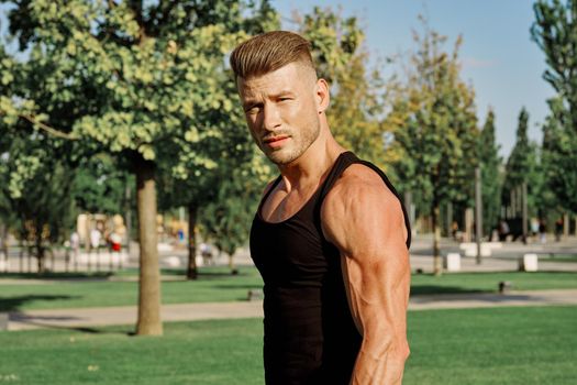 athletic man in black t-shirt with dumbbells in the park training. High quality photo