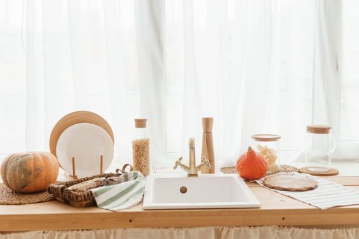 Kitchen countertop by the window in a bright room. Orange pumpkins, bread and pasta on the countertop. Autumn mood at home.
