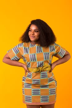 Young african american girl with an afro hairstyle. Portrait on yellow background with copyspace.