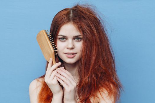 pretty woman combing naughty hair blue background. High quality photo