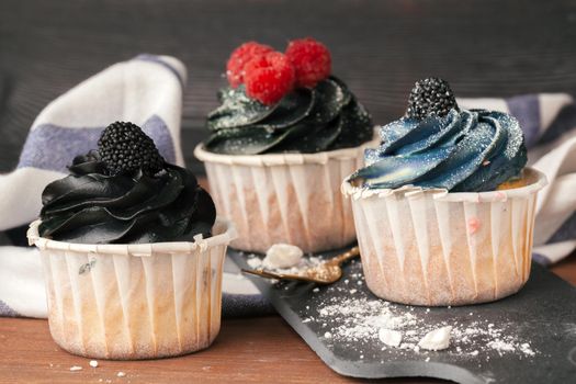 Delicious raspberry and caramel cupcakes on dark background