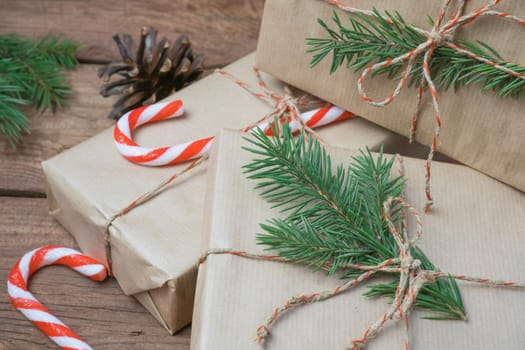 Christmas gifts or gift box wrapped in kraft paper with decorations, pine cones and fir branches on a rustic wooden background