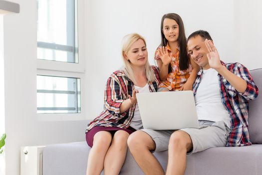 Happy family using laptop together on sofa in house