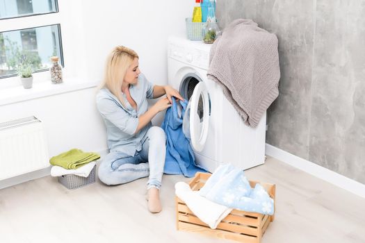 A young housewife with washing machine and clothes. Washing day.