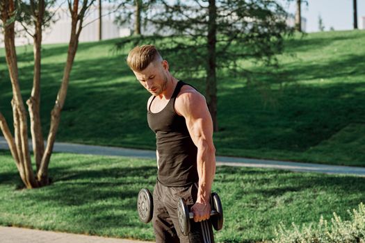 pumped up sports Vykhino in the park with dumbbell workout. High quality photo