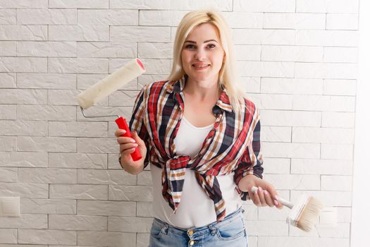 Beautiful young woman painting wall in room