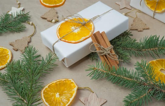 New Year's composition. On beige craft paper, gift boxes, dry orange slices, pine cones, cinnamon, cloves, spruce branches. Cozy Christmas concept