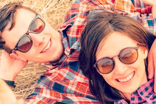 Happy hipster couple in sunglasses rests on nature