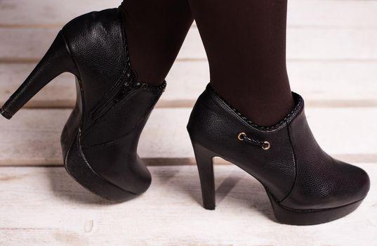 autumn black female high-heeled shoes on a white wooden floor.