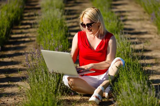 Portrait of a woman buying online or booking hotel with a laptop and credit card on the beach in vacations. E commerce concept