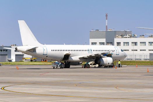 Airplane is parked near gate of airport terminal on sunny day