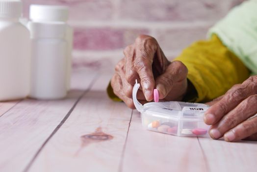 senior women hands taking medicine from a pill box .