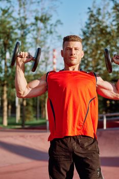 Muscled Man With Dumbbells Outdoor Workout. High quality photo