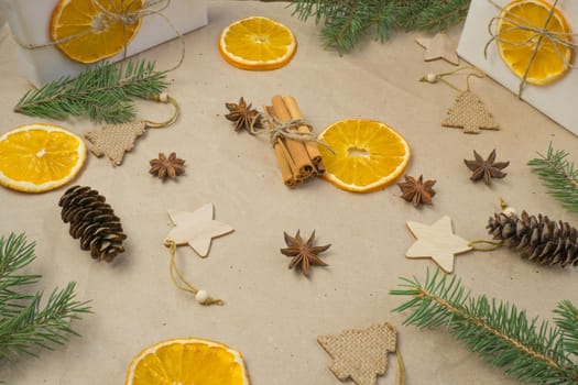 New Year's composition. On beige craft paper, gift boxes, dry orange slices, pine cones, cinnamon, cloves, spruce branches. Cozy Christmas concept