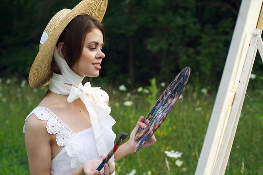 woman with a palette of paints painting a picture outdoors close-up. High quality photo