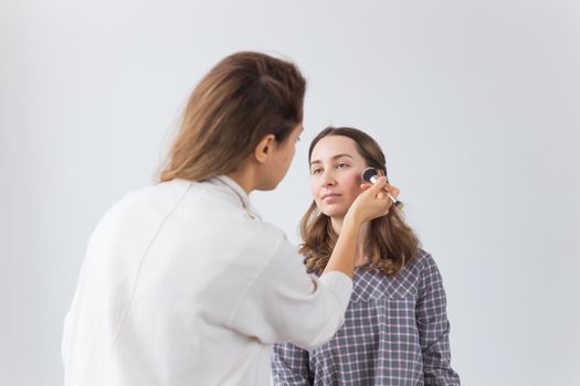 Beauty and cosmetics concept - Makeup artist doing professional make up of young woman.