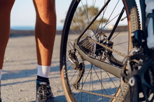 Cyclist man feet and bike wheel on coastal road close up