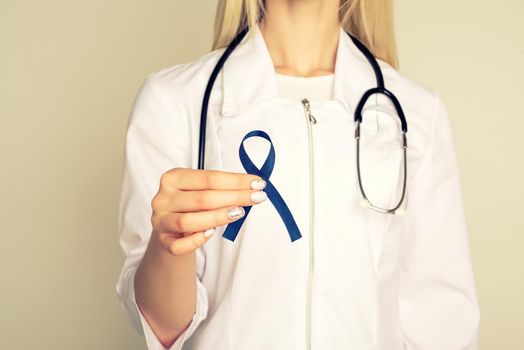 Doctor hands holding blue ribbon, diabetes and Colorectal Cancer Awareness - Image