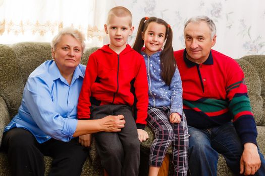 Grandparents and their young grandchildren relaxing at home