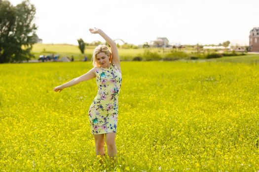 Young woman with her arms wide spread is enjoying in the sunny summer day, rear view