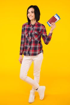 Young smiling excited woman student holding passport boarding pass ticket isolated on yellow background. Education in university college abroad. Air travel flight - Image