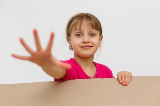 A cheerful child sits inside a mail box. The head of a little girl peeks out of a corton box. The baby arrived in a new house in a postal parcel. Portrait of a child with blue eyes.